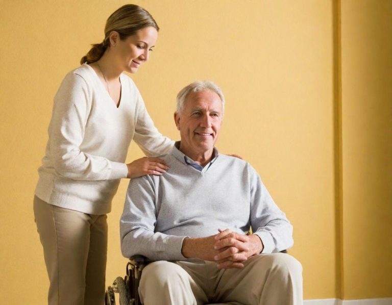 A woman smiles at an elderly man in a wheelchair, enhancing his comfort and support.
